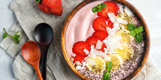 Lactose-free tropical berry smoothie bowl topped with fresh fruit, chia seeds, granola, and mint.